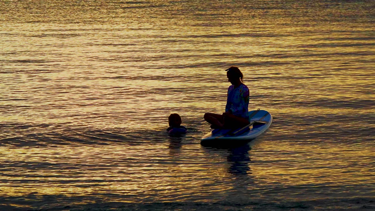 At El Sargento, Mexico, the seated board rider remains centered while the swimmer surfaces closer to the board in warm gold water.