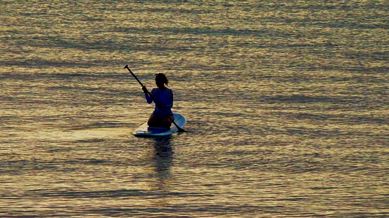Paddleboarder centered on reflective sunset water