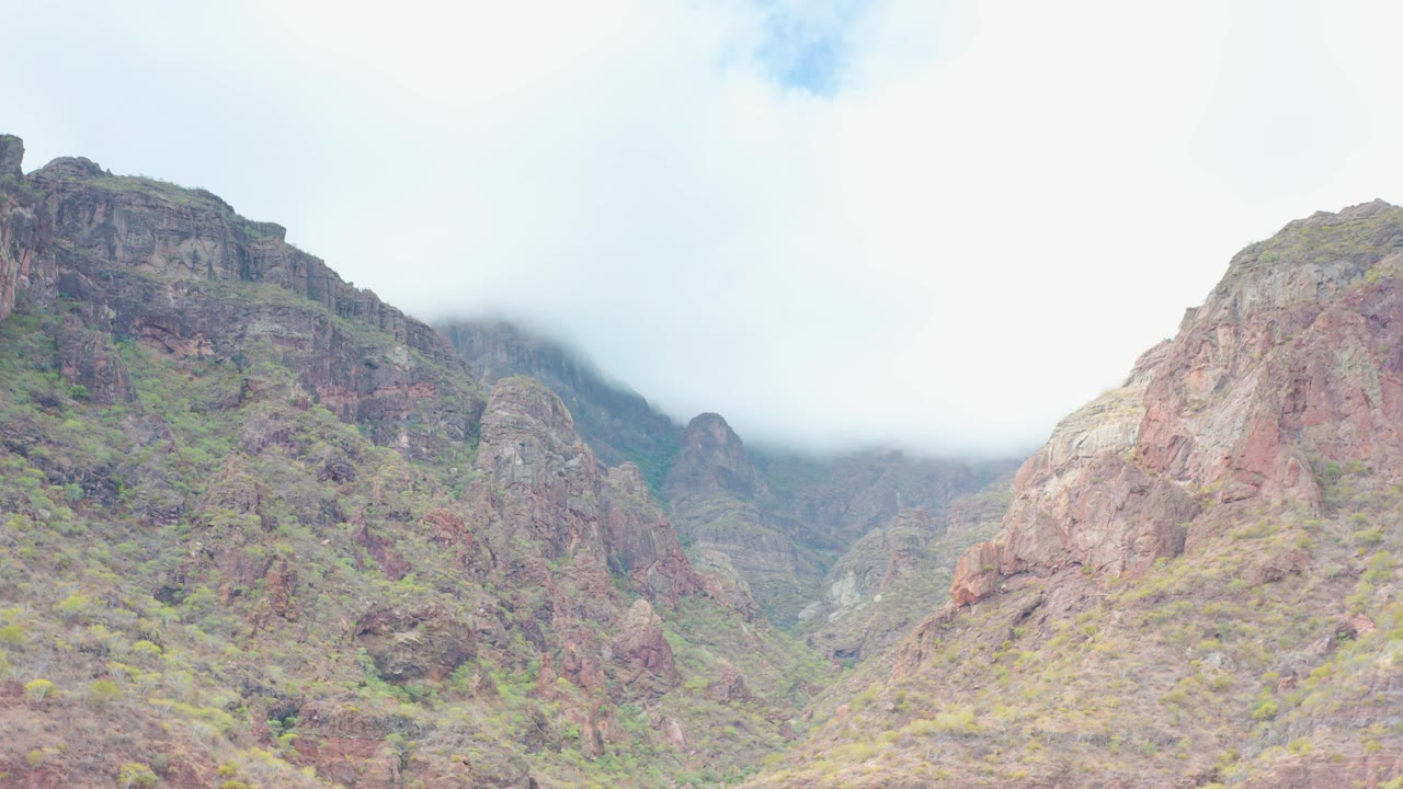 Wide view of a rocky mountain valley in Puerto Escondido, Baja California Sur, with low mist over distant ridges and no visible people.