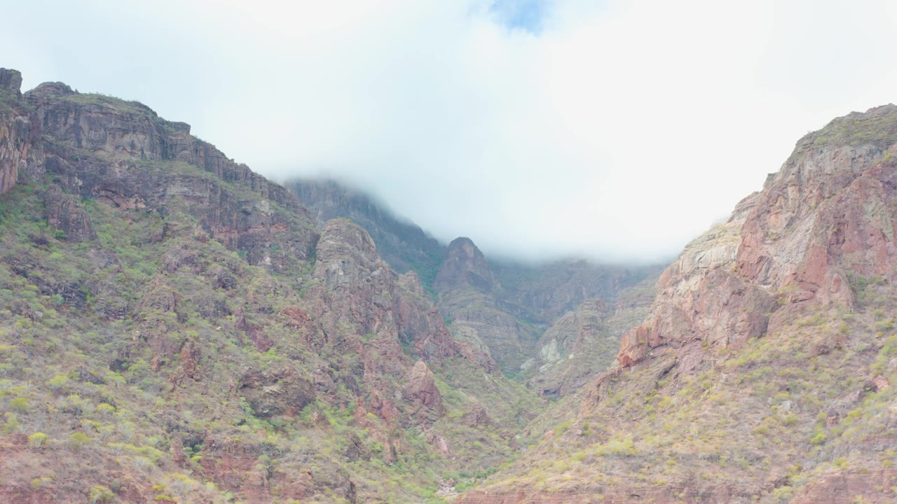 The frame holds on rugged mountain ridges in Puerto Escondido, Baja California Sur, where mist softens the background peaks and no people are visible.