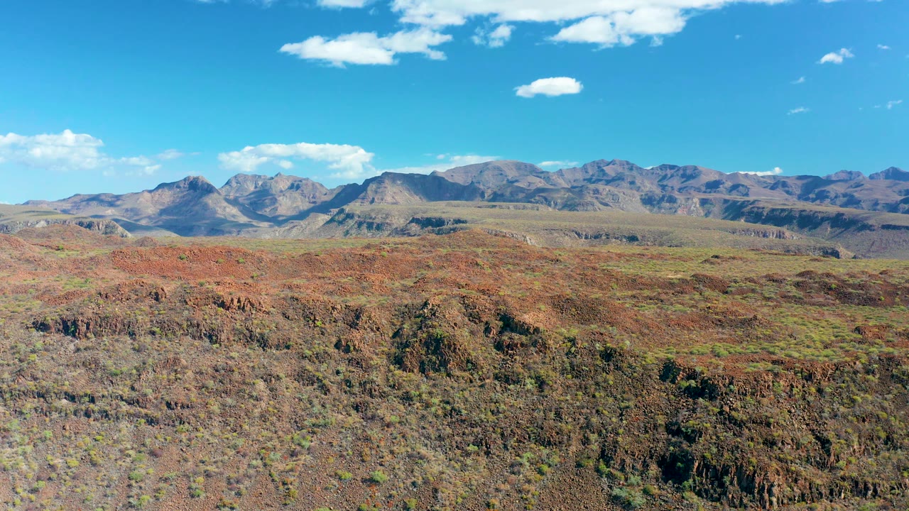 Third frame shows San Javier's red and brown ground textures stretching into a flat middle distance, with mountains below a clear blue sky and no visible people.