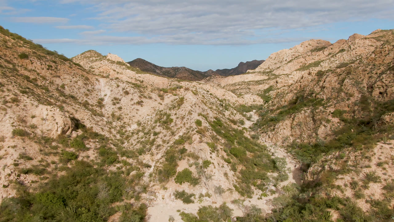 A central tan ridge dominates the Cabo Pulmo mountain view, with scrub vegetation on the slopes, darker hills on the horizon, and no visible people.