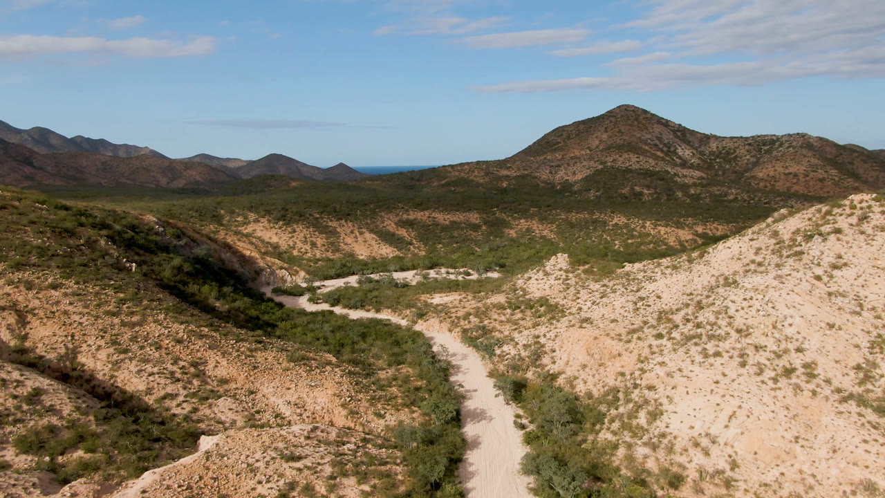 Sandy hill and winding dirt road below mountains
