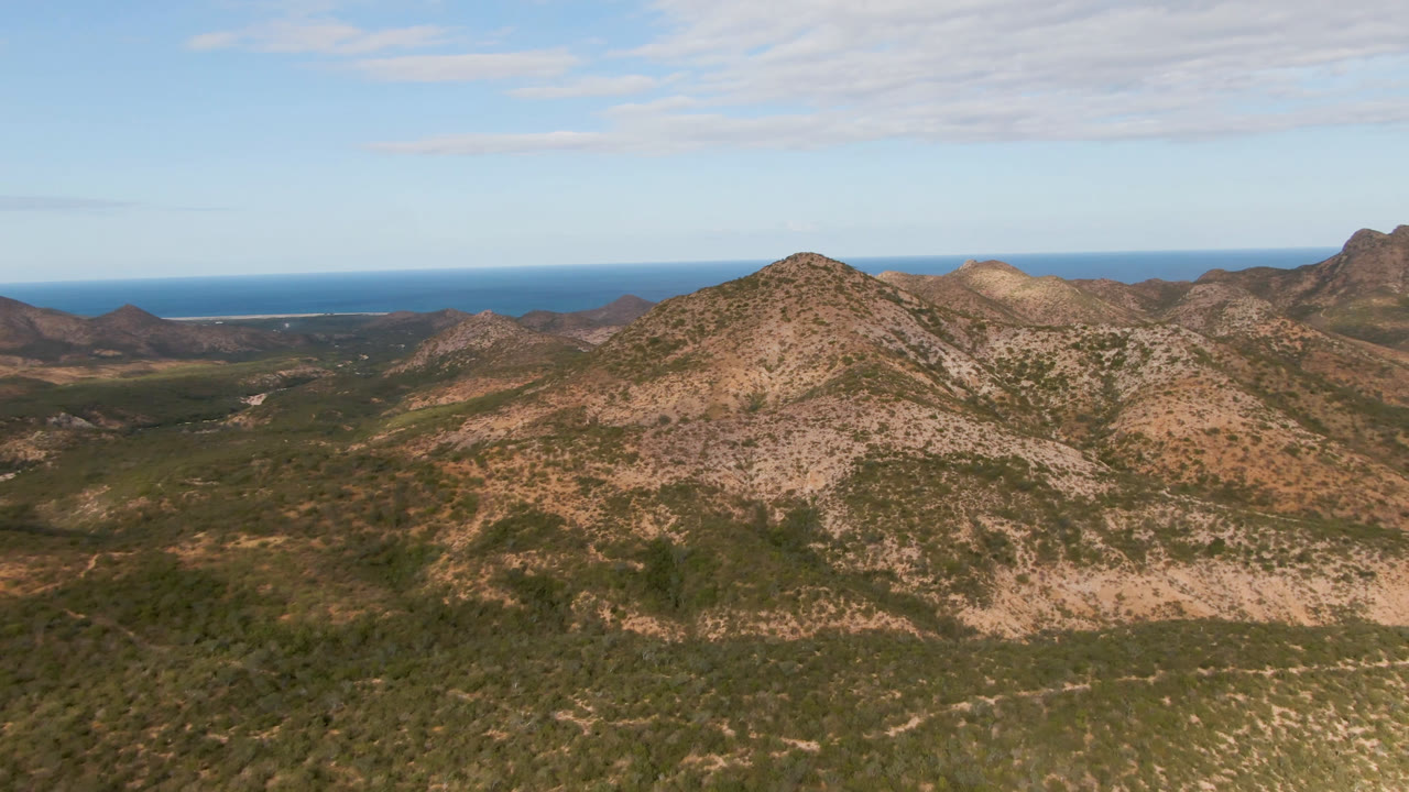 Desert mountains with green valleys and ocean behind the ridges