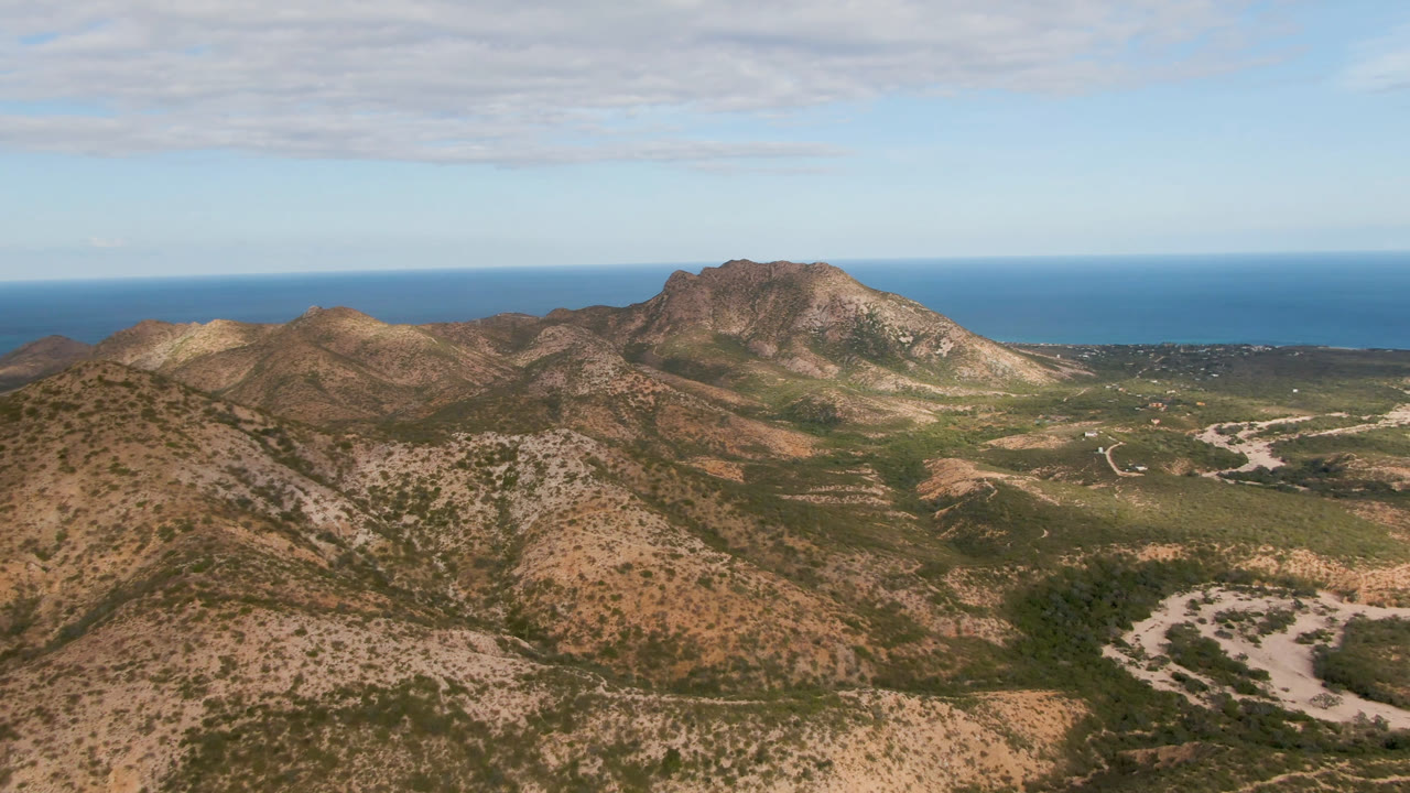 Scrubby hills and rocky mountain range above a coastal horizon.