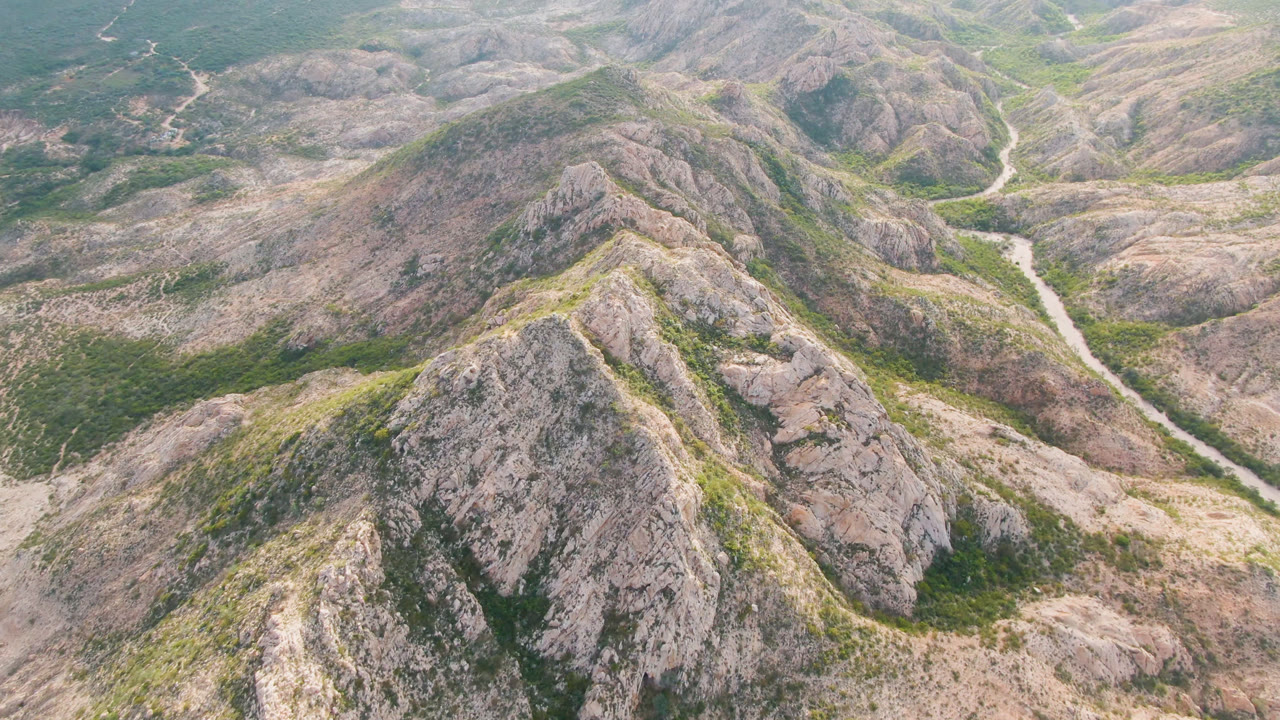 Aerial landscape of gray hills and a narrow winding road.