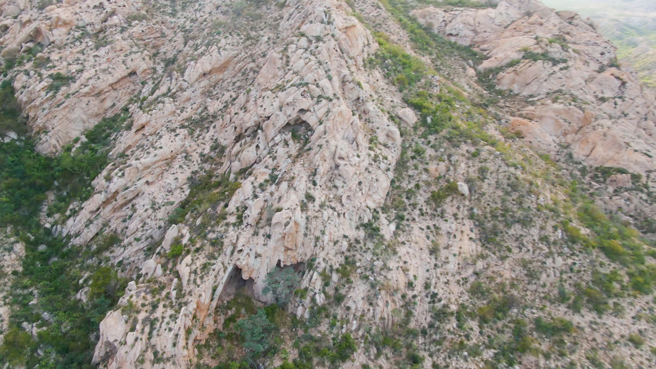 Aerial frame over a pale rocky mountain side in Cabo Pulmo, Baja California Sur, Mexico, with a green ravine running through the center and no visible people.