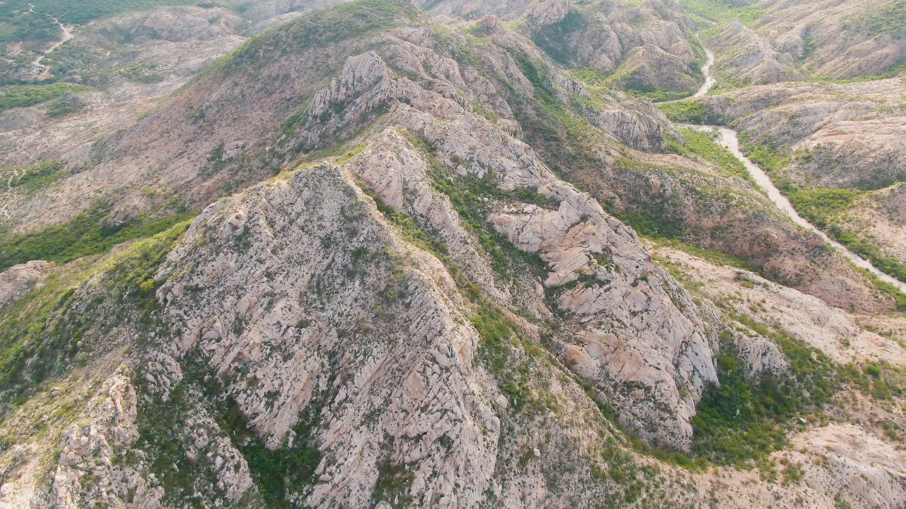 High view of a dirt road passing behind rocky hills.