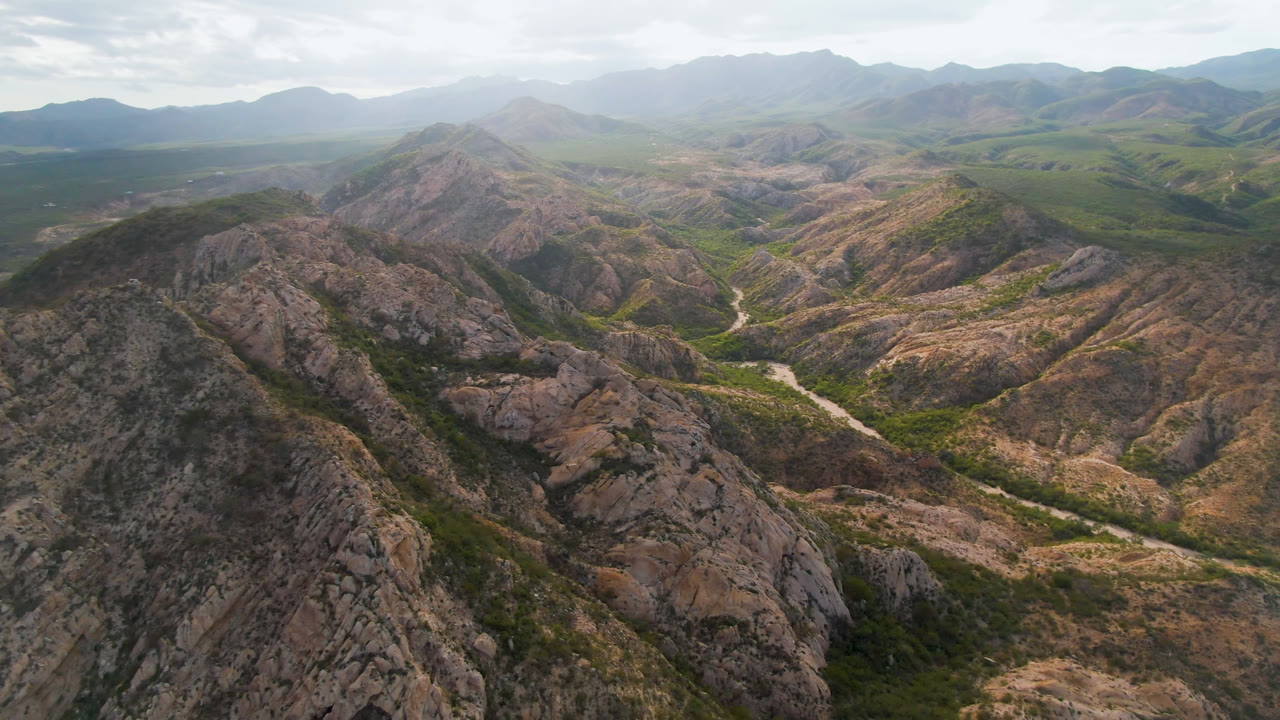 Drone view of arid mountain ridges with a river bend through the valley