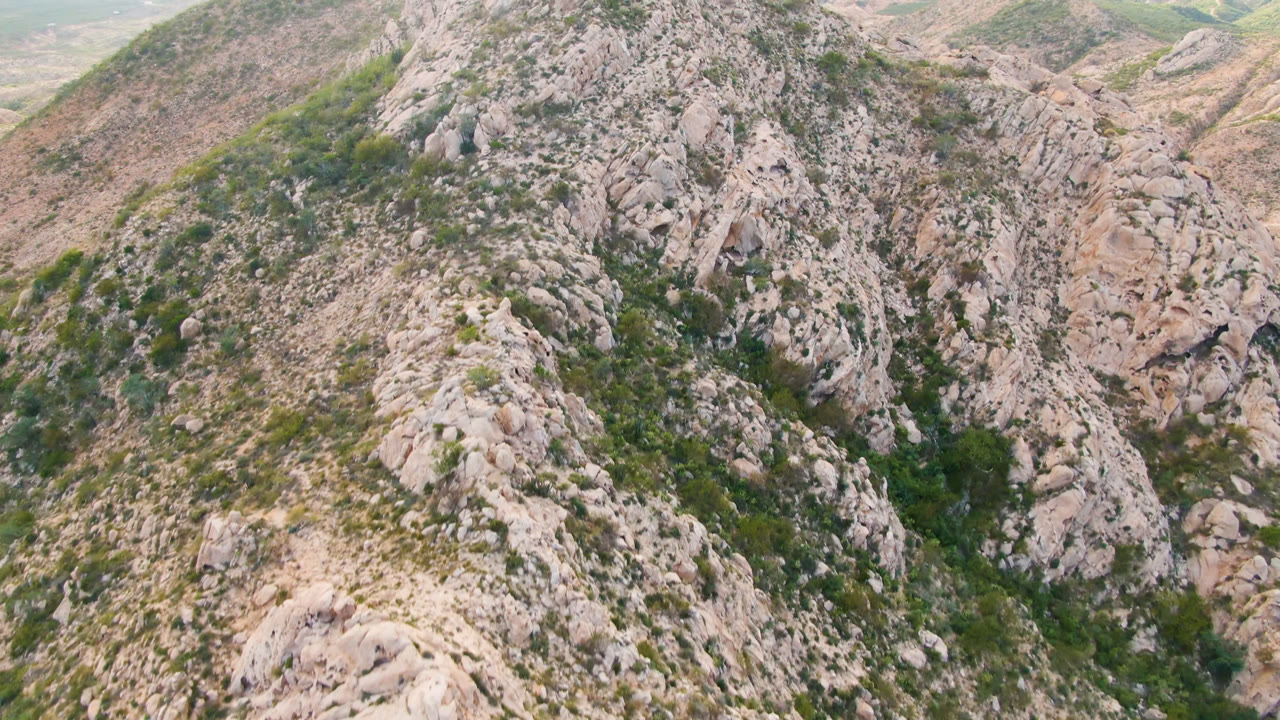 Aerial frame from Cabo Pulmo, Baja California Sur, with the steeple-like rocky crest centered over scrub-covered slopes and no visible people.