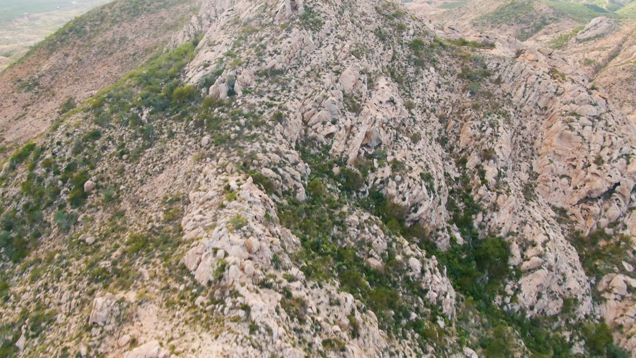 Rugged rock face and green shrub patches on a dry mountain slope