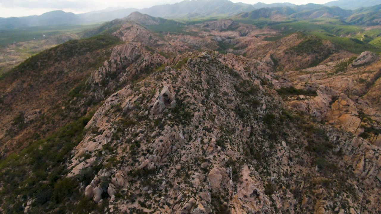 Drone view of a rugged ridge with mountains across the horizon