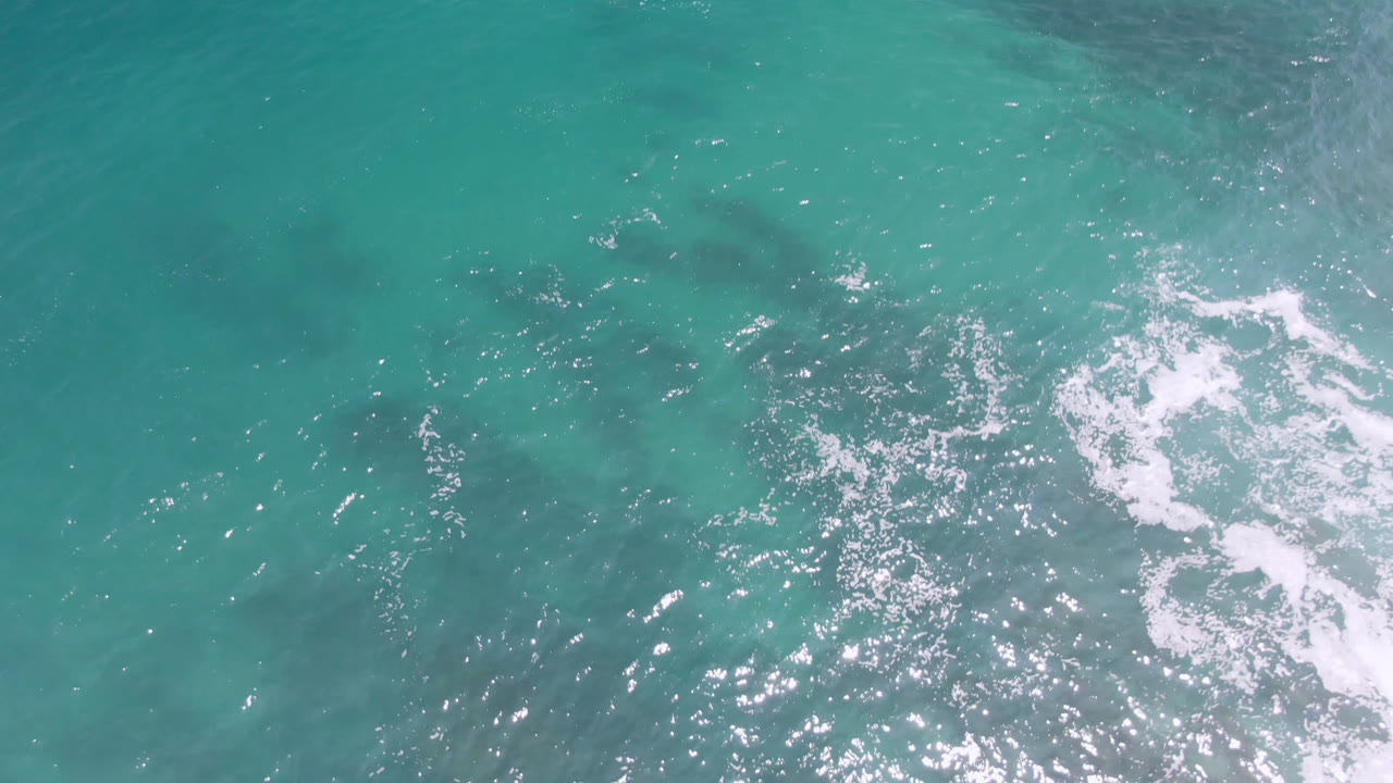 Aerial ocean surface with a bright foam streak near the center.