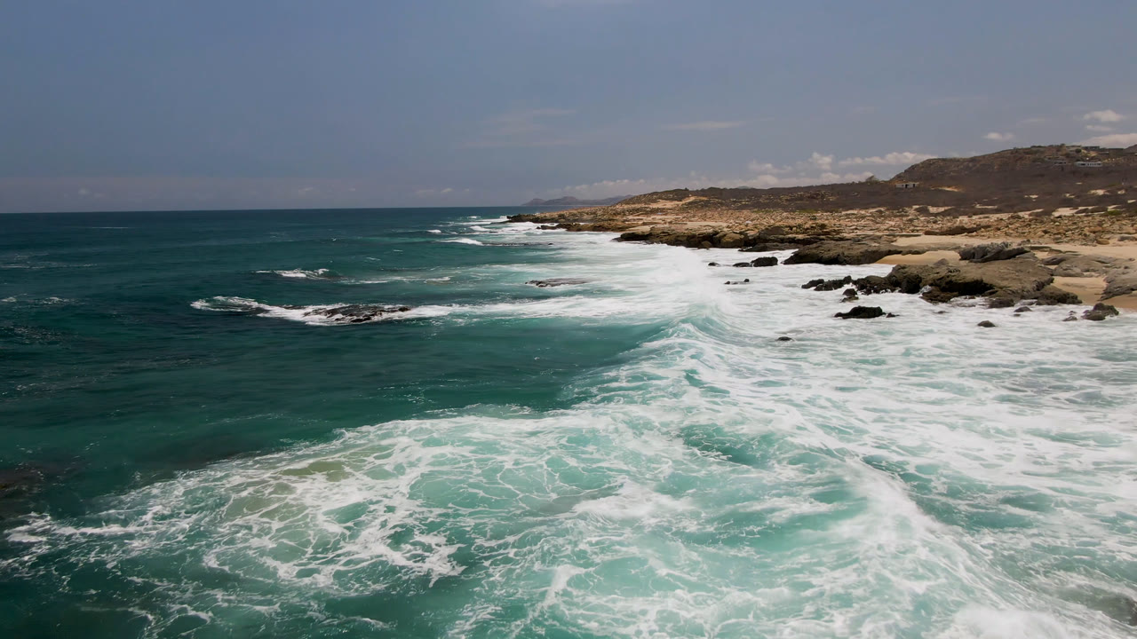 Foamy surf surging toward a rocky Baja California Sur coast