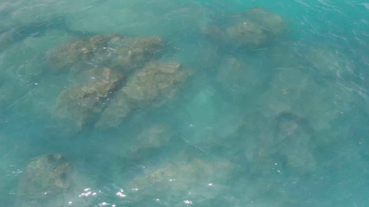 Submerged rocks beneath rippled turquoise sea