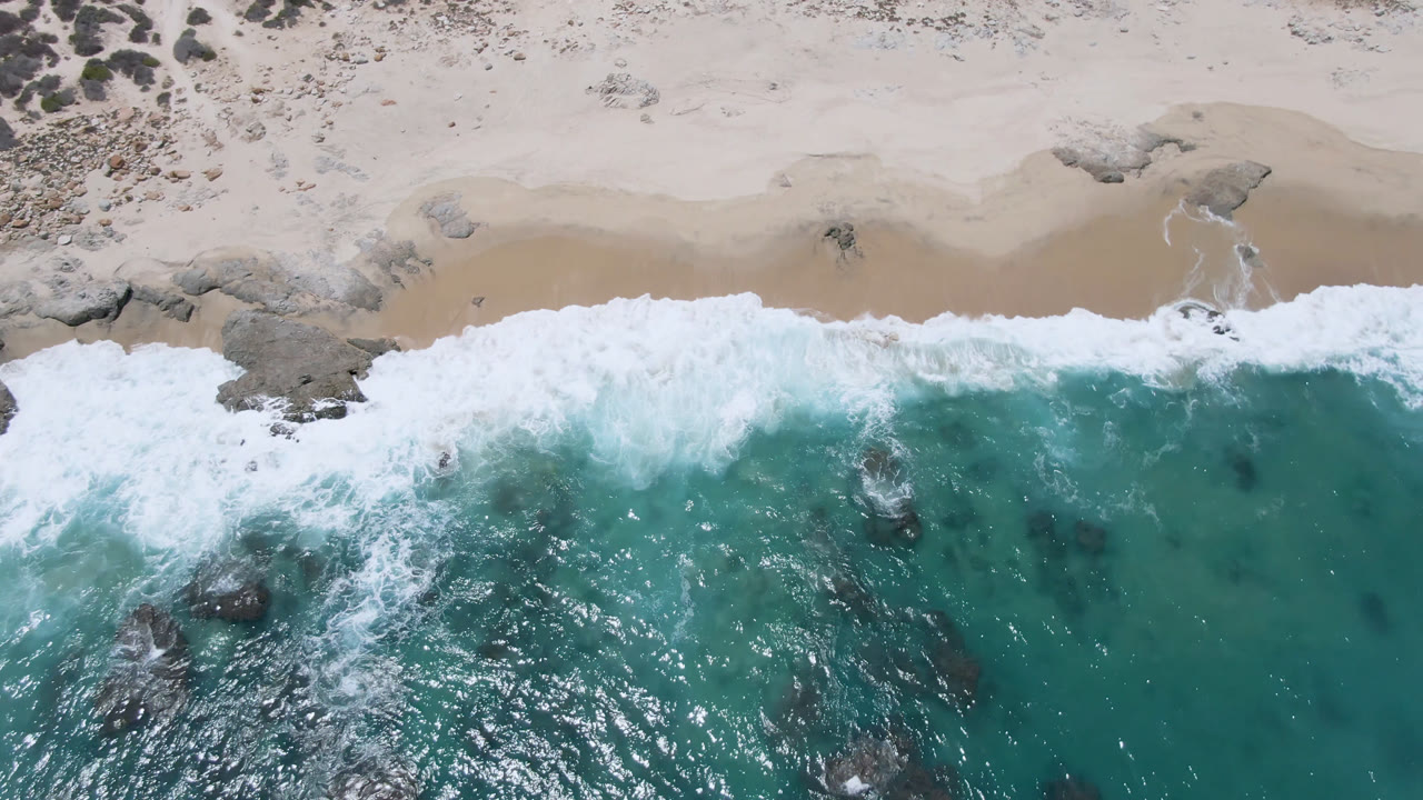 Wide band of white surf beside turquoise water and sand