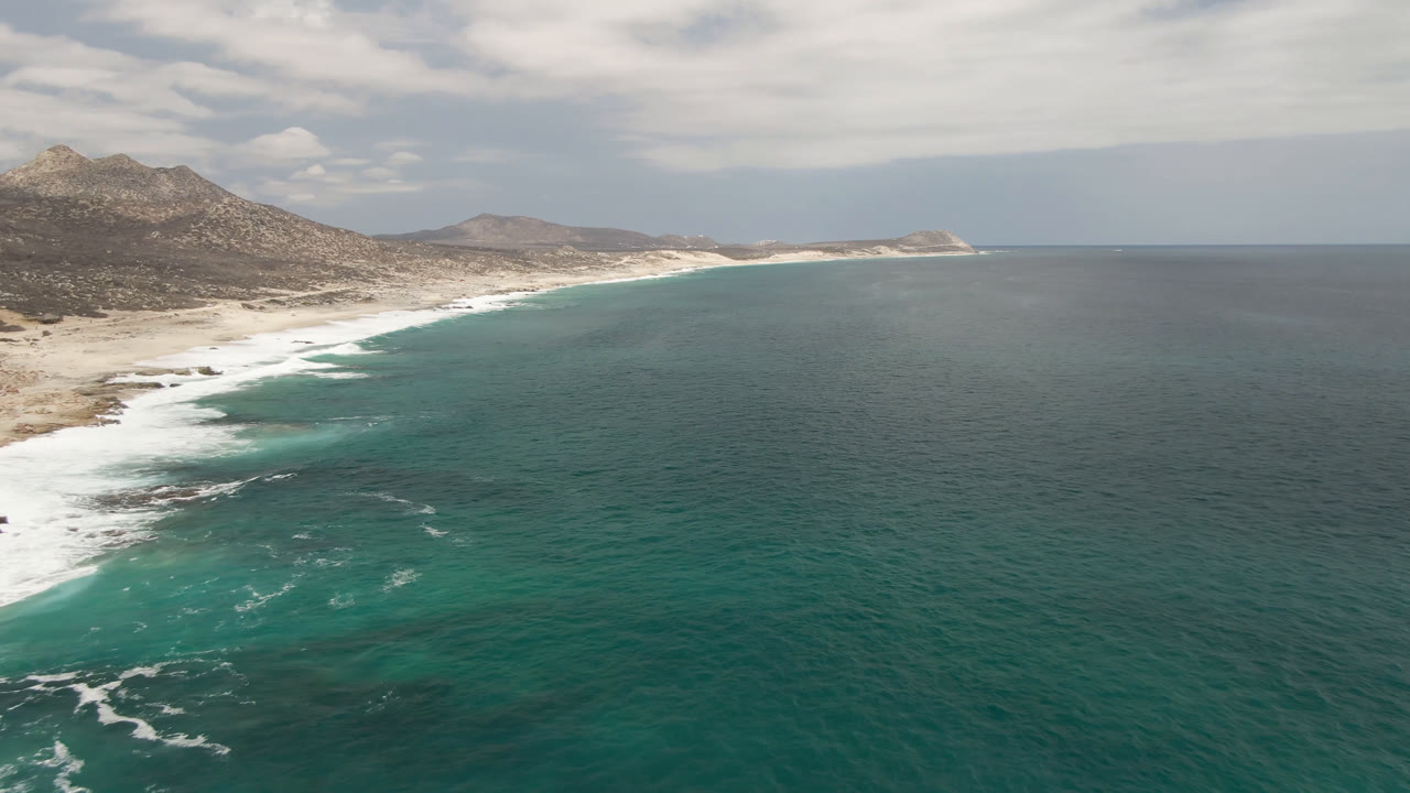 Drone-height ocean view with white surf on a remote sandy coastline