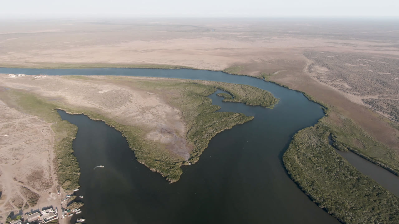 Second frame shows the same Aldofo Lopez Mateos waterway from above, with more of the central sandy point and green scrub margins visible, plus no visible people.