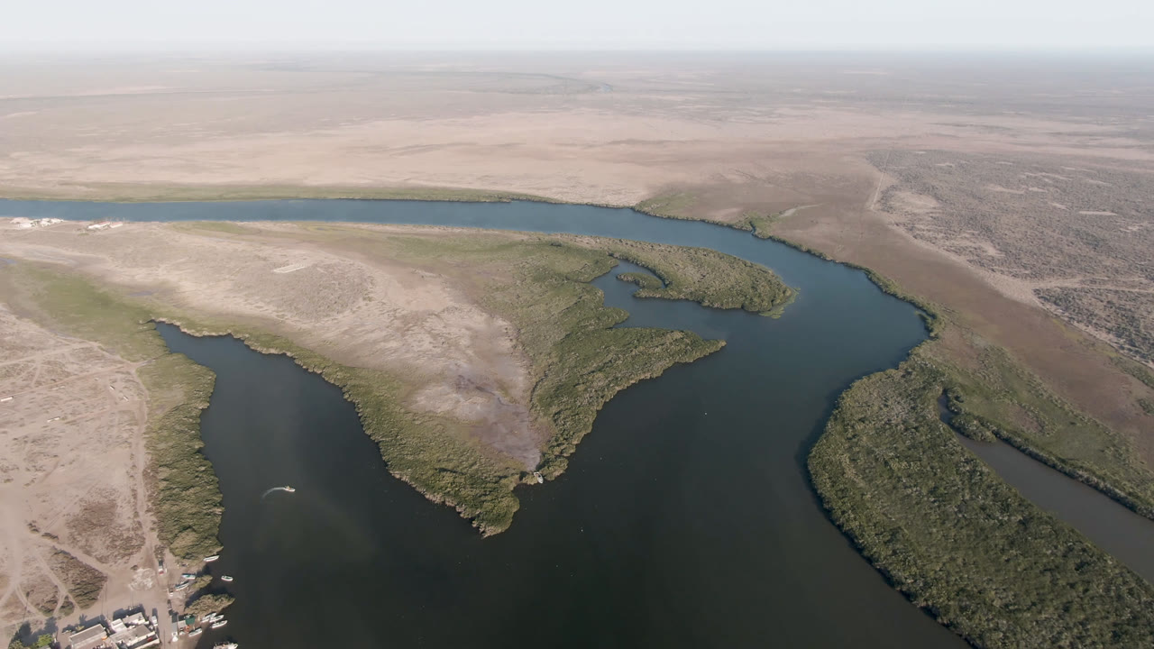 High aerial view of a riverlike channel beside desert scrub