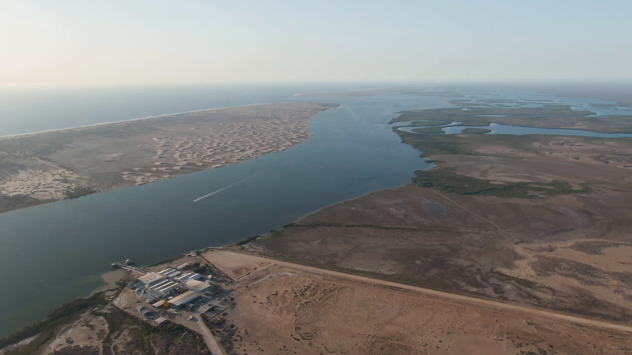 Aerial coastal delta view with broad water, sand shoreline, and wetlands