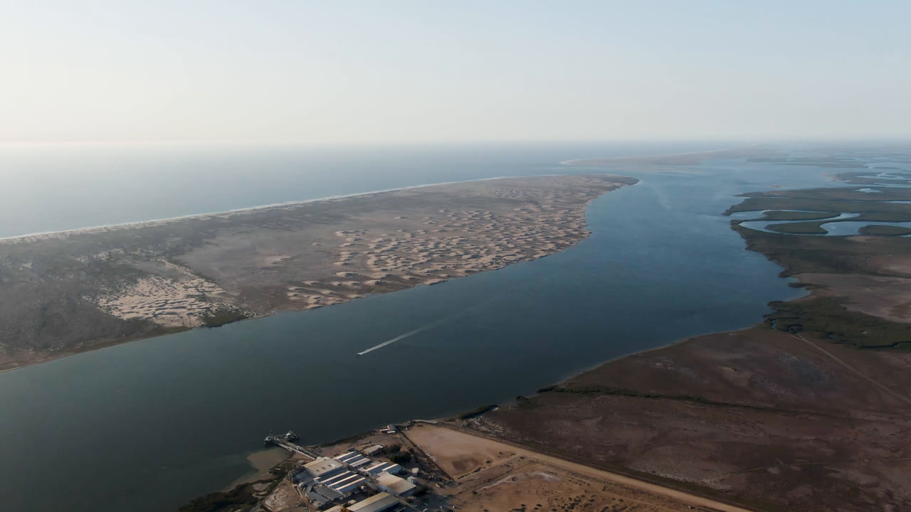 Third frame holds a wide aerial view in Baja California Sur, with shoreline buildings near the lower edge, open water through the center, surf at left, and no visible people.