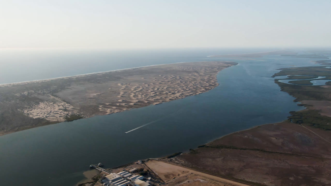 Fourth frame shows the channel widening across Aldofo Lopez Mateos, with a sandy peninsula, brown marshland in the foreground, distant ocean line, and no visible people.