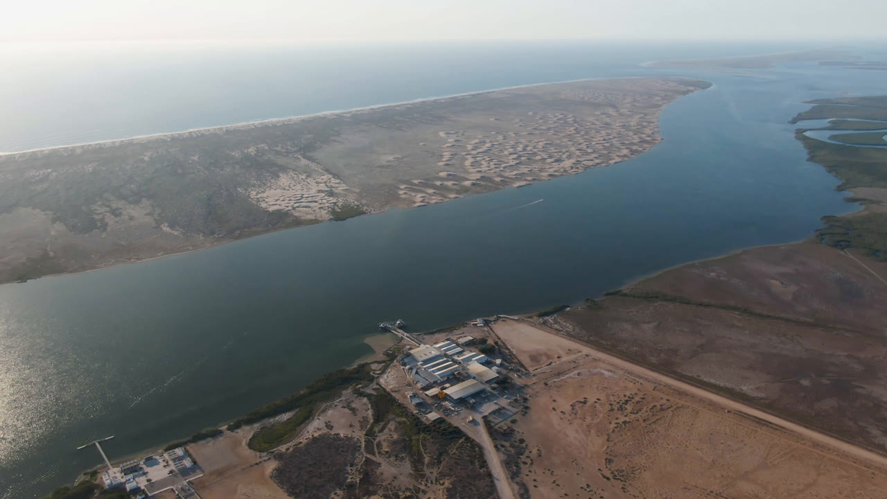 High aerial view of a coastal channel beside a long sandy landform