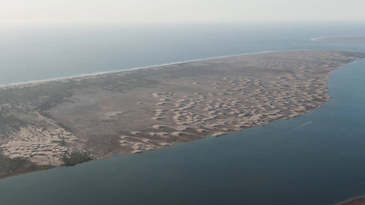 Aerial frame over Aldofo Lopez Mateos, Baja California Sur, showing patterned sand banks across the midground, calm water in the foreground, a pale beach at left, and no visible people.