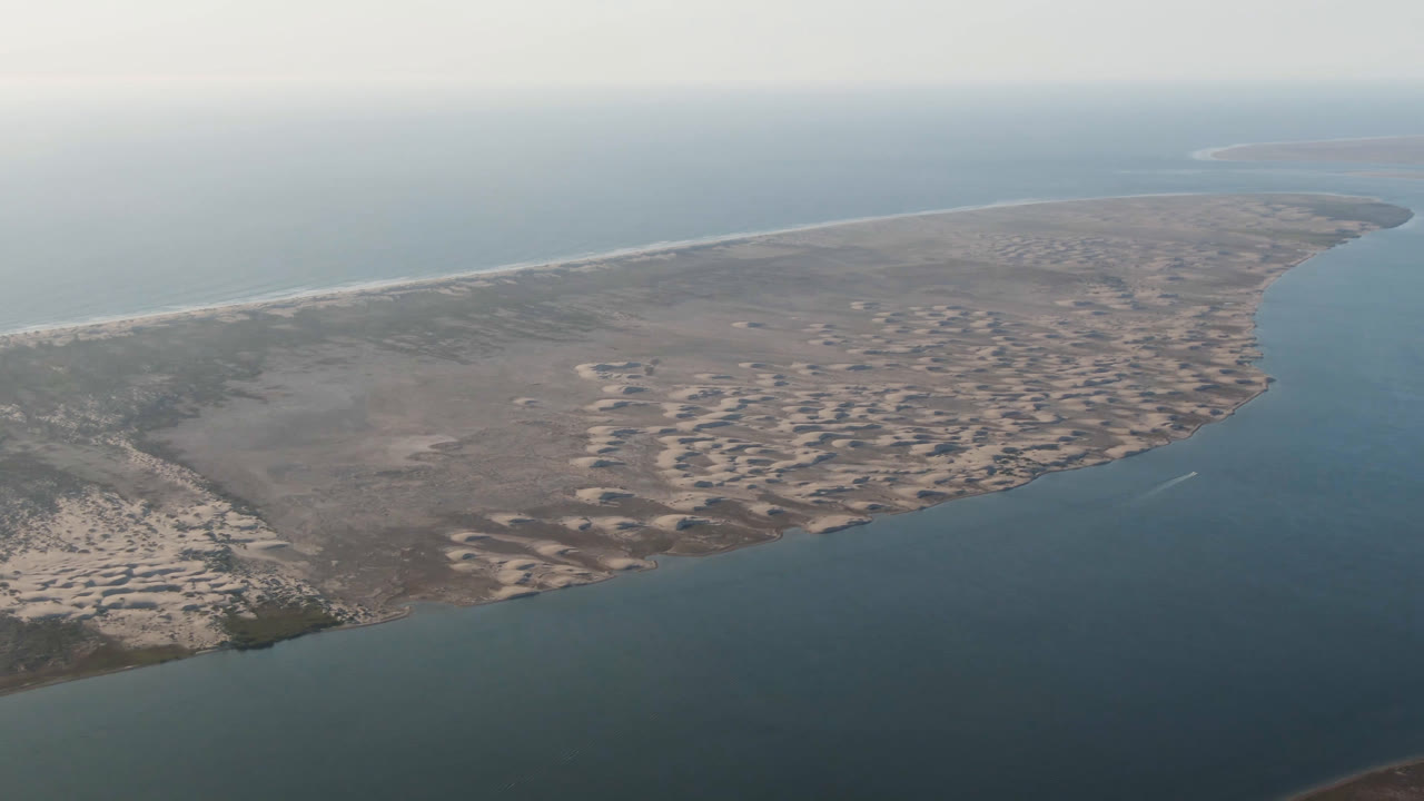 Wide aerial coastline with curved sandy point and surrounding water