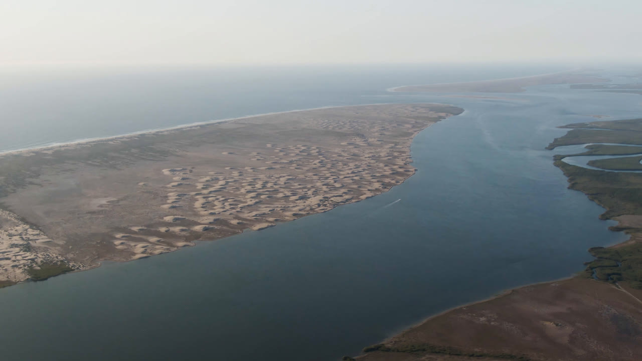 Aerial frame in Aldofo Lopez Mateos showing the central blue-green channel, pale sand flats on the left bank, darker marsh channels to the right, and no visible people.