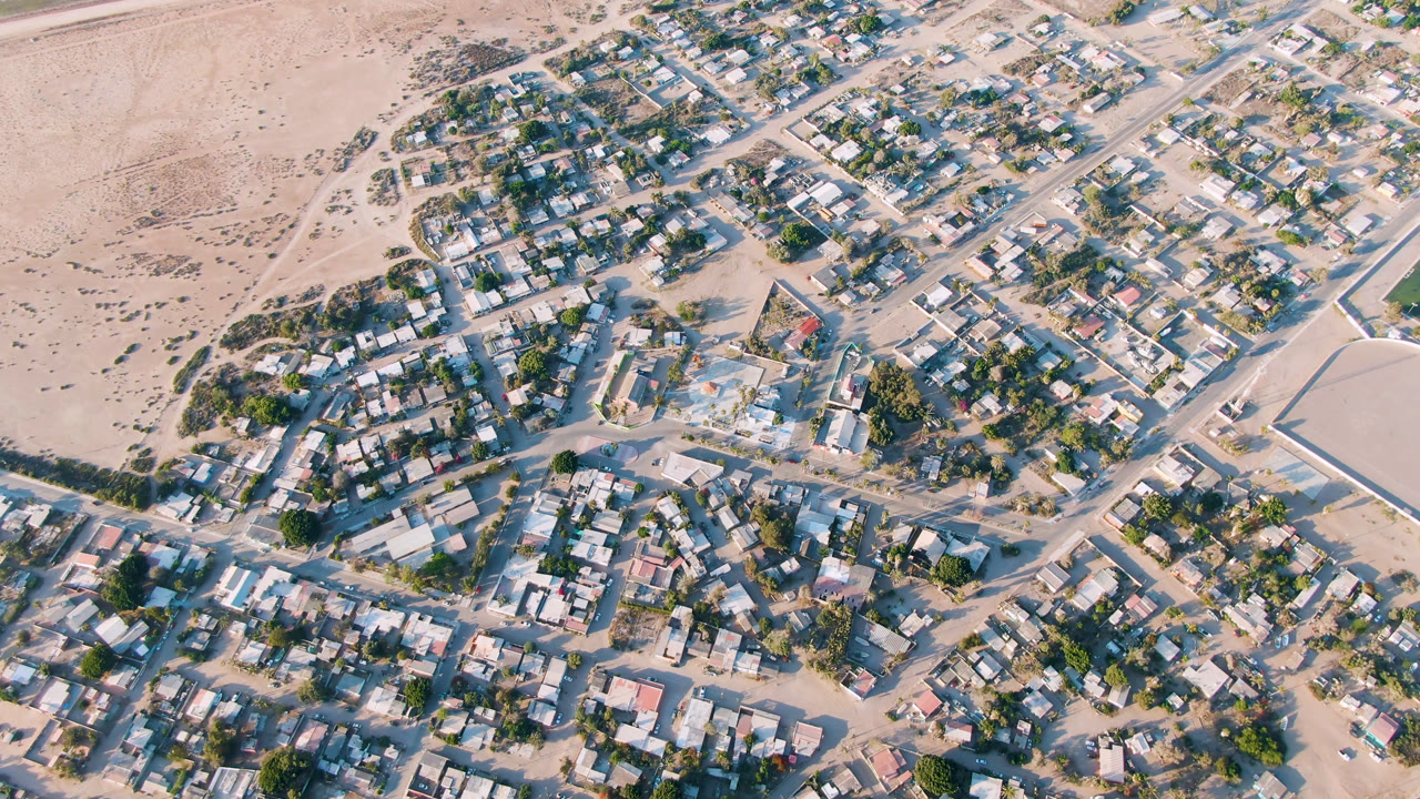 Overhead view of houses, sandy roads, trees, and desert edge.