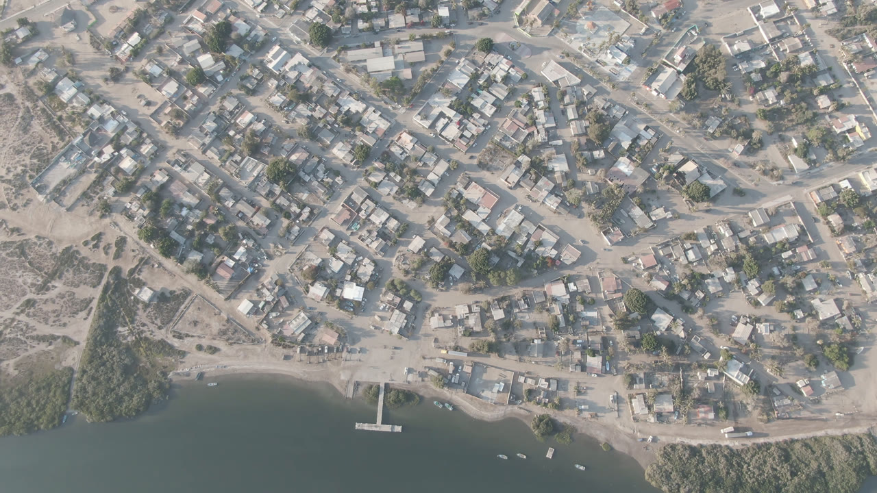 Overhead view of a small coastal town beside green-blue water.