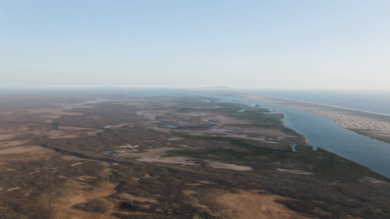 High view of a river delta landscape with ocean horizon and long sandy shoreline.
