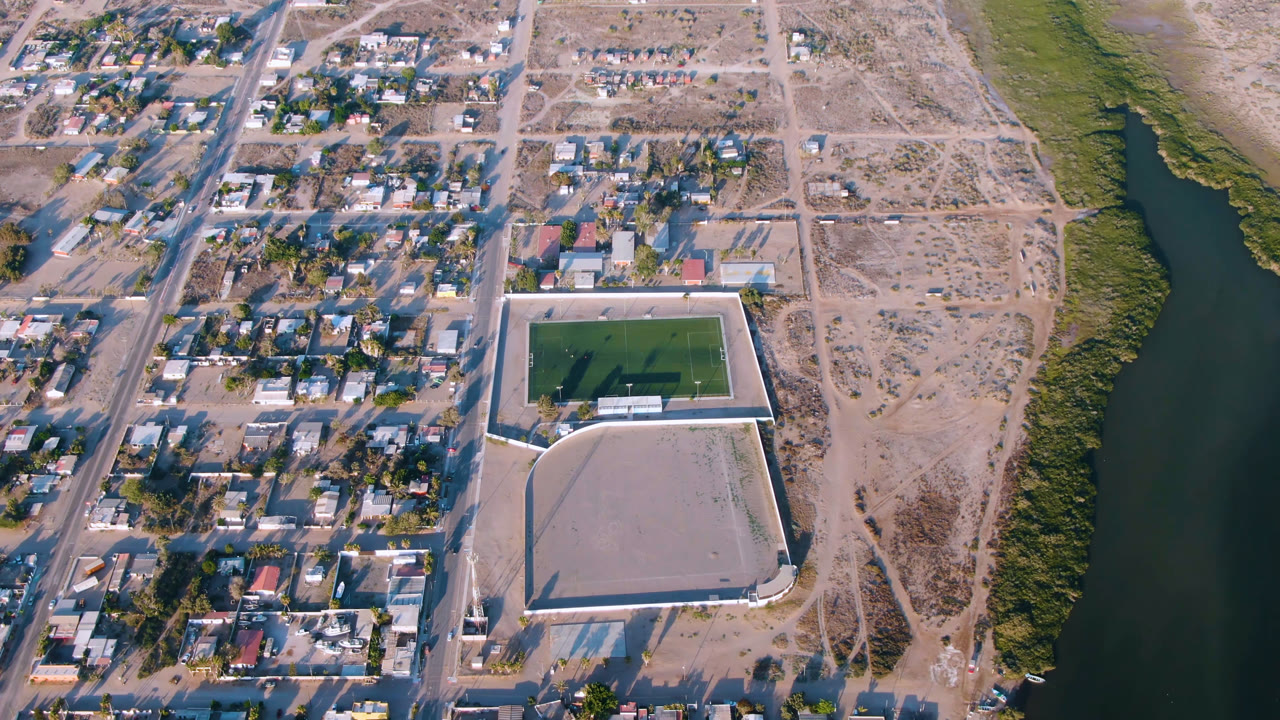 Wide aerial frame of a small city grid beside scrubland and a river.