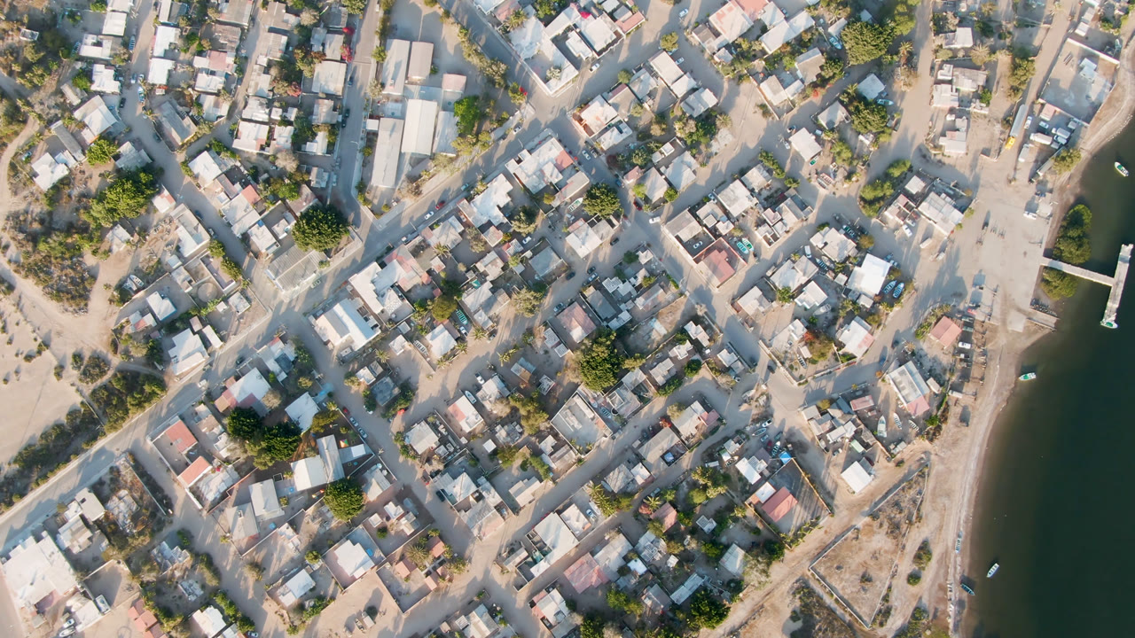 Overhead town blocks beside a dark river channel and small bridge.
