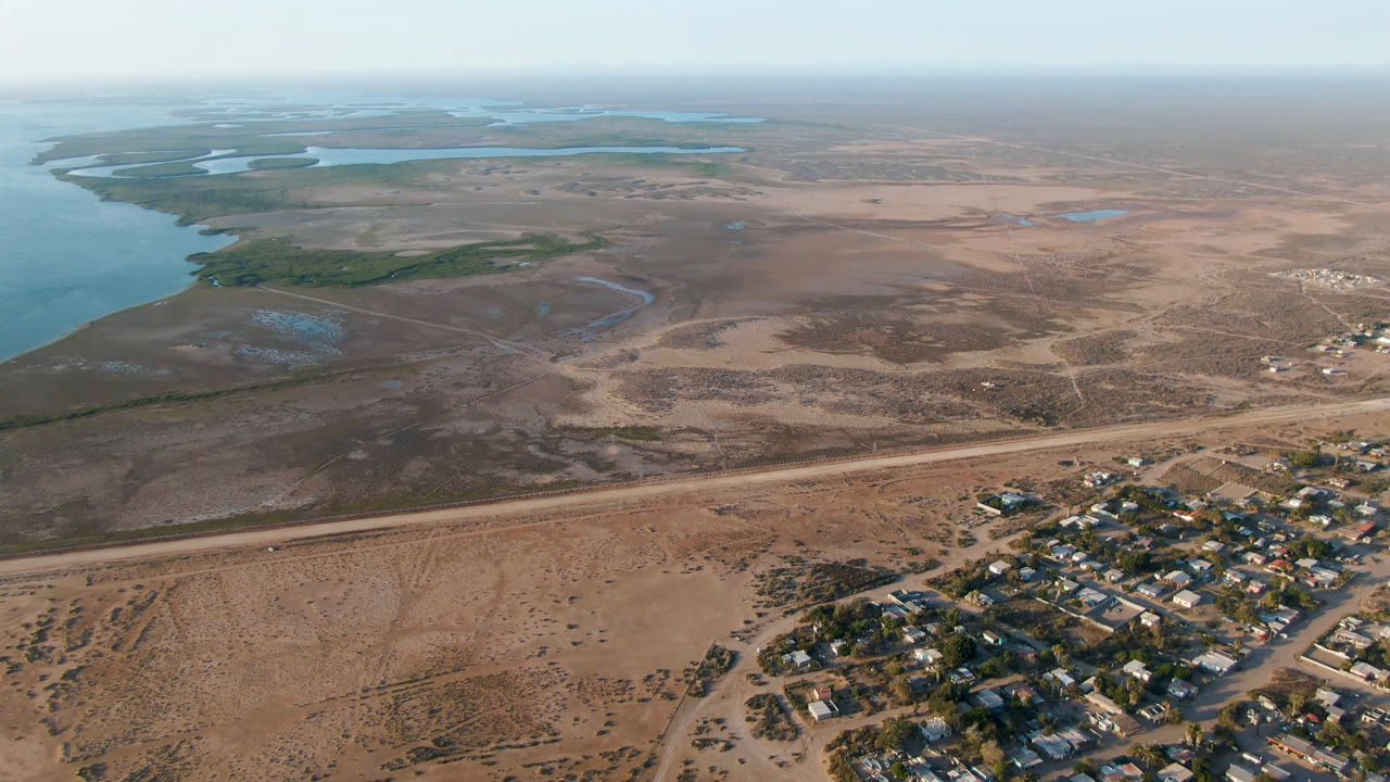 High drone view of desert flats, water channels, roads, and town buildings.