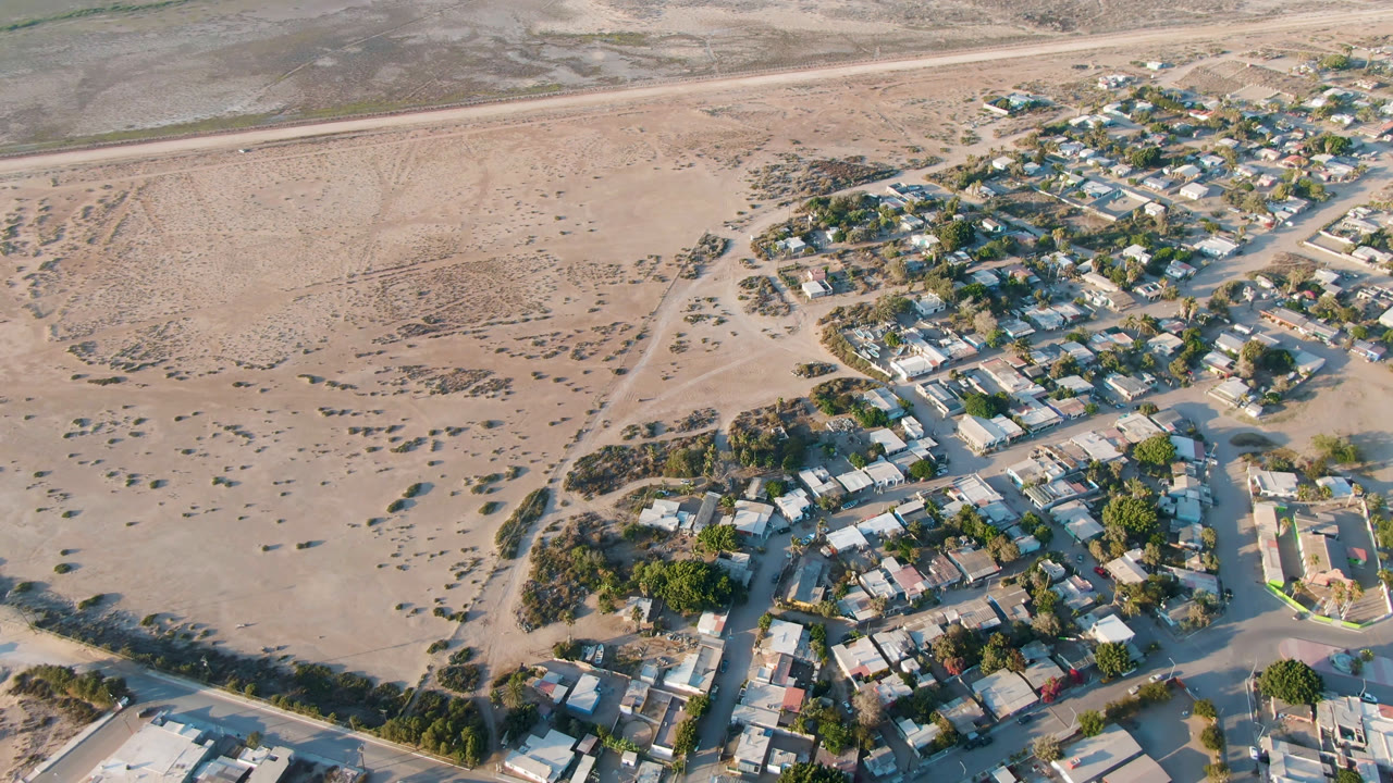 Aerial view of houses, roads, trees, and sandy terrain.