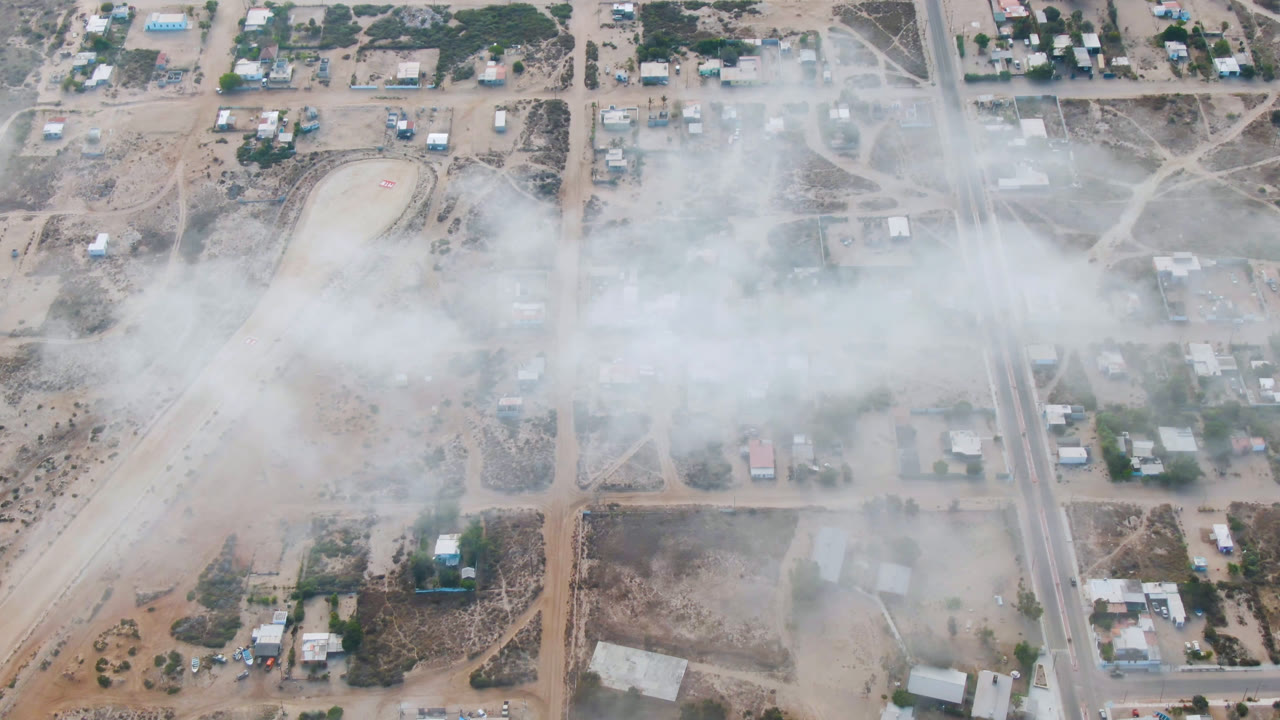 Smoke cloud over small buildings and a straight road