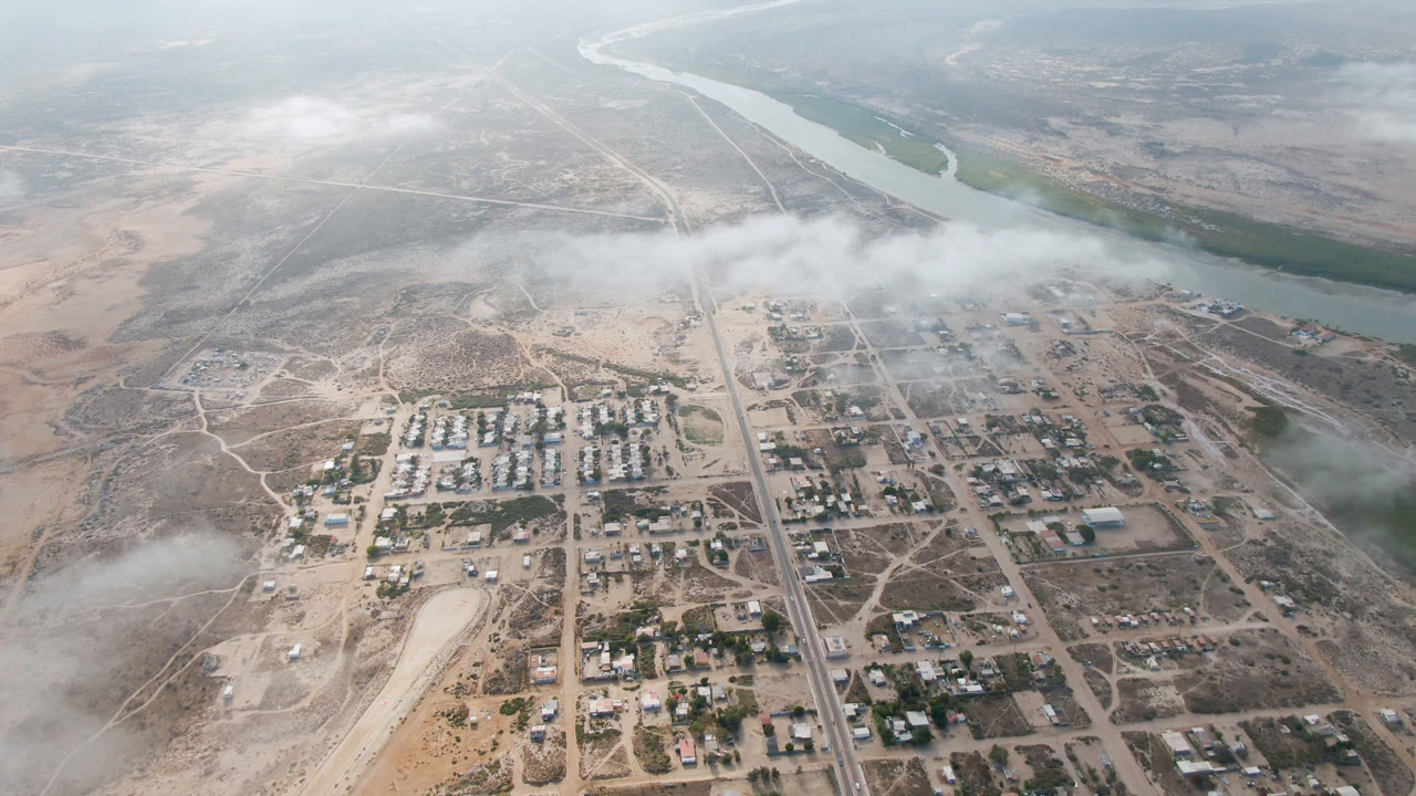 Overhead town and river landscape with low clouds crossing the middle of frame.