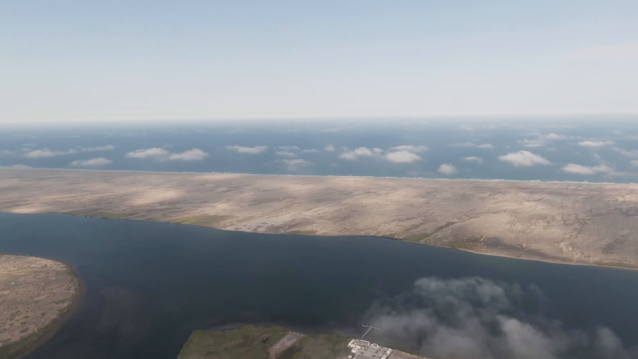 High aerial view of open water, dry shoreline, and low clouds in the distance.