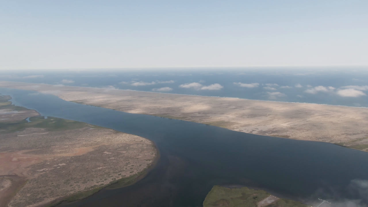 Aerial view one second into the clip over Aldofo Lopez Mateos, Baja California Sur, showing the river bend shifted slightly across arid shoreline, with distant water and no visible people.
