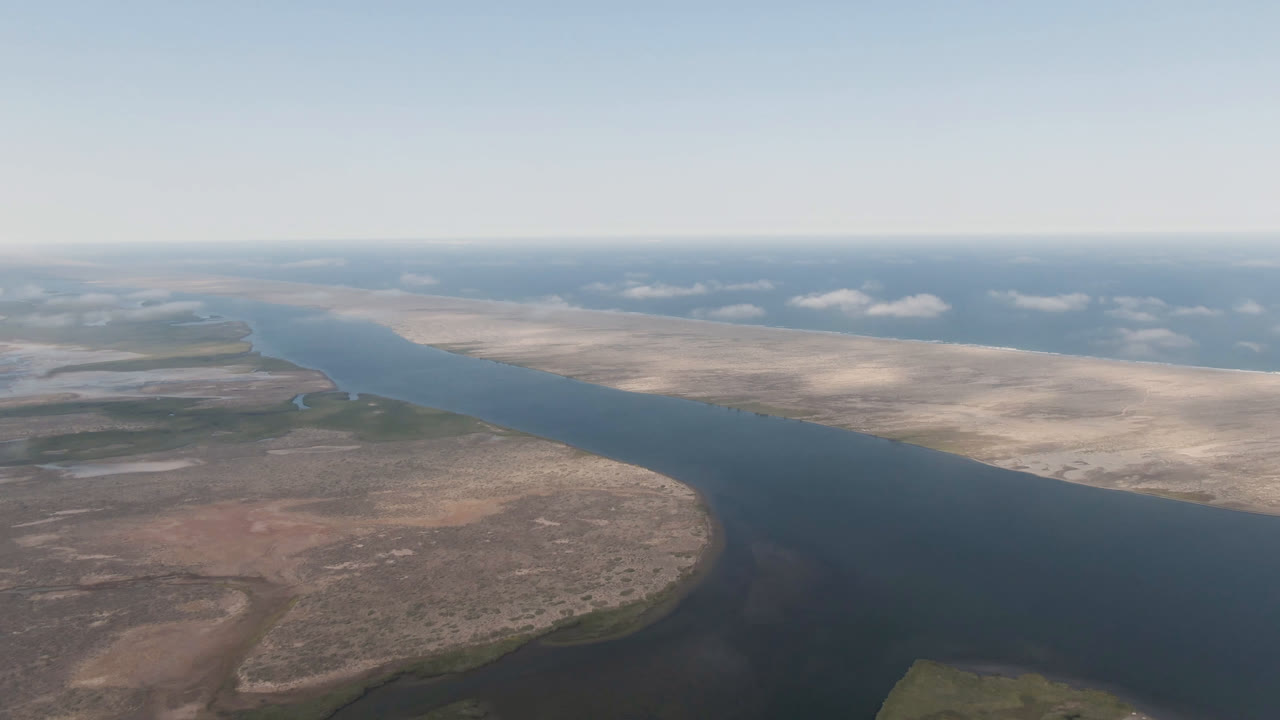 Drone-height view across a broad river and arid landscape with a low horizon.