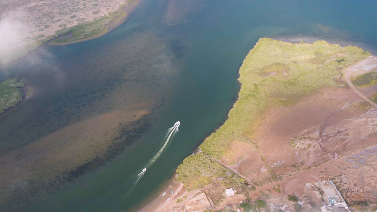 Aerial frame from Aldofo Lopez Mateos, Baja California Sur, showing the boat near the middle of the waterway, its wake angled toward a curved bank, with no visible people.