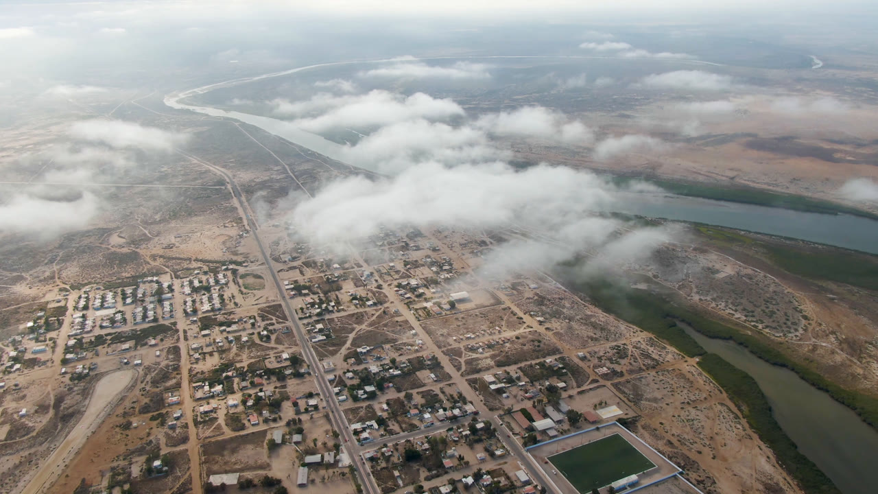 Aerial view of a small town beside a river under low clouds.