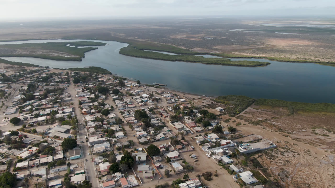 Aerial view of a small town beside a wide waterway and low islands.