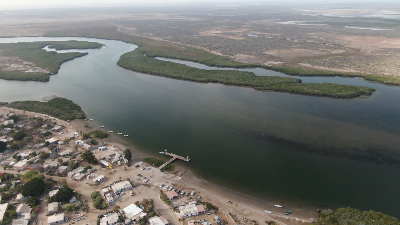 Drone view across a broad river with town roads, boats, and green islands