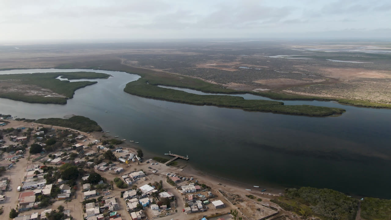 Aerial view of a coastal town beside a dark river and sandy beach