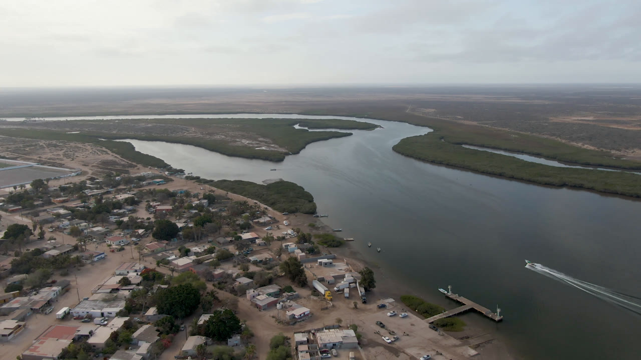 Aerial view of a river delta beside a small town with a boat wake on the water.