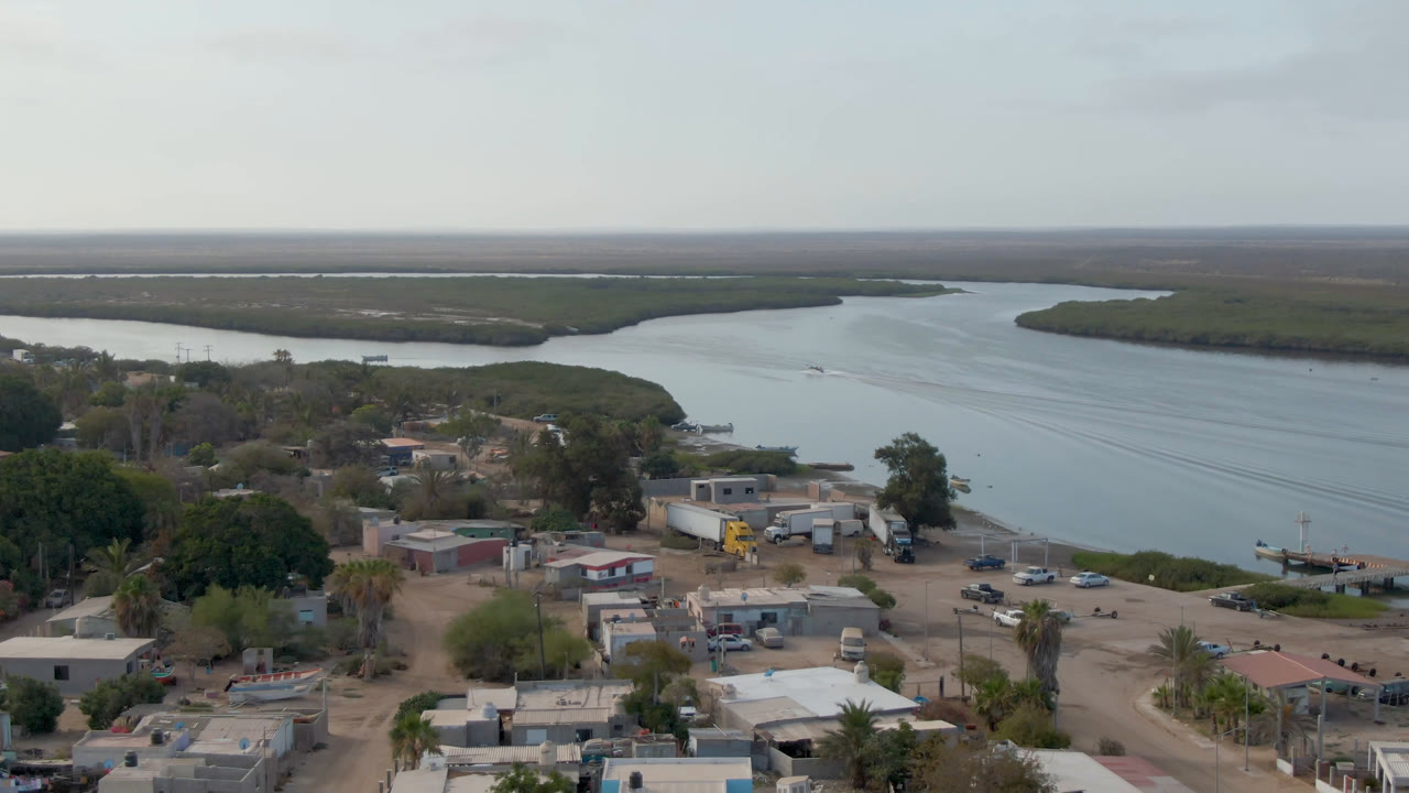 Elevated view of a small riverfront village and wide waterway.