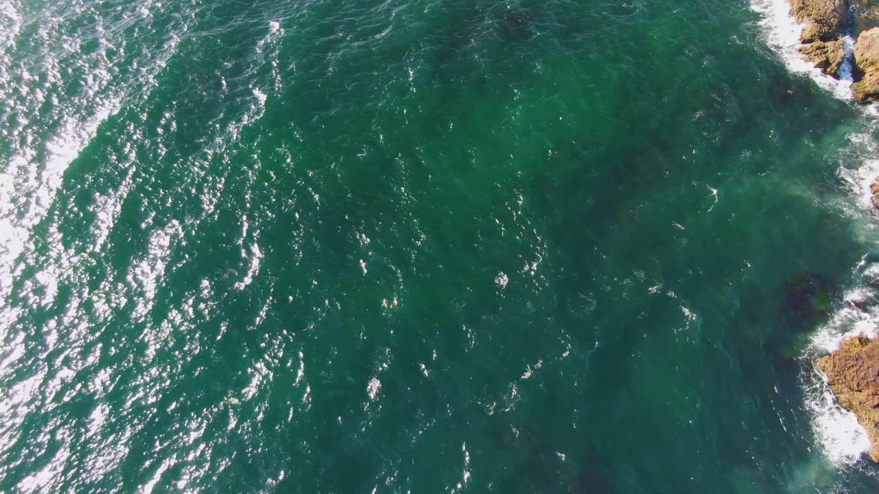 Aerial water view with a larger rocky shoreline segment entering from the upper right.